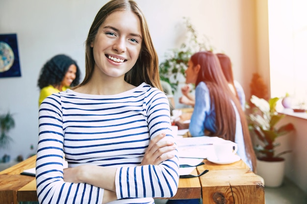 Aantrekkelijke zelfverzekerde moderne zakenvrouw in casual kleding kijkt naar de camera en glimlacht. Moderne start-up business team. Collega's of studenten