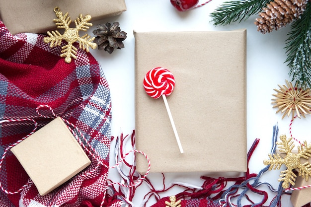 Foto aanwezig in bruin knutselpapier, dozen, snoep, plaid en kerstversiering op tafel. kopieer ruimte. eco-vriendelijk nieuwjaar concept