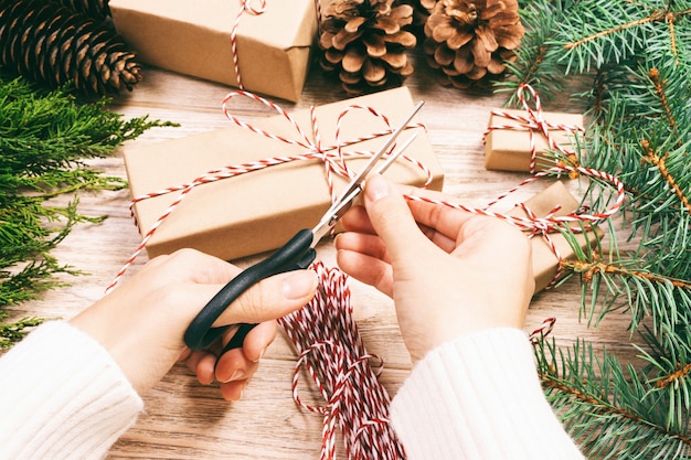 Aanwezige vrouwen verpakkende Kerstmis, meisje bereidt Kerstmisgiften met spar en denneappel voor. Handgemaakt geschenk op houten met kerstdecor. Bovenaanzicht, copyspace. afgezwakt