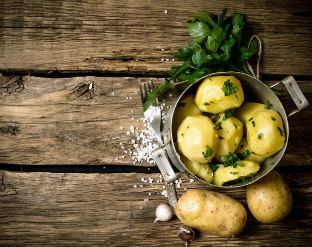 Aardappel eten. Gekookte aardappelen met kruiden en zout op een houten tafel. Vrije ruimte voor tekst. Bovenaanzicht