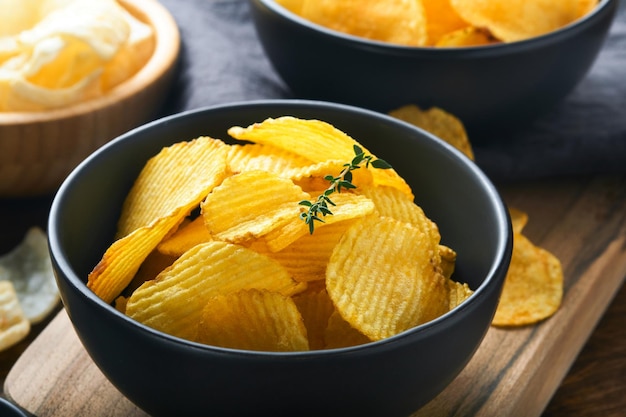 Aardappel golfkarton Fastfood Krokante aardappel chips keramische zwarte kom met zure roomsaus en uien in houten stand op oude keukentafel houten achtergrond Amerikaanse traditie Hot BBQ Top uitzicht