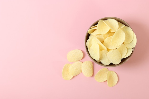 Aardappelchips in een bord op een gekleurd bovenaanzicht als achtergrond