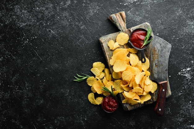 Aardappelchips met ketchup en mosterdsaus Biersnacks op een zwarte stenen achtergrond Bovenaanzicht