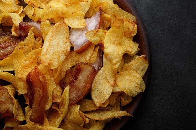 Aardappelchips met spek op een bord op een grijze achtergrond