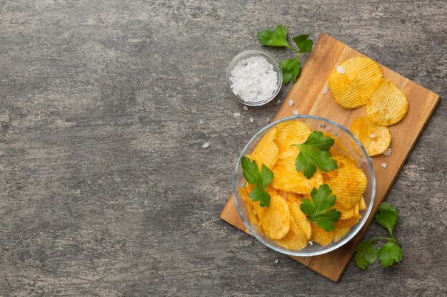 Aardappelchips met zout op gekleurde achtergrond bovenaanzicht met kopieerruimte