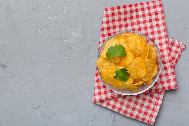 Aardappelchips op kom met servet op gekleurde achtergrond Heerlijke knapperige aardappelchips in kom Ruimte voor tekst Bovenaanzicht