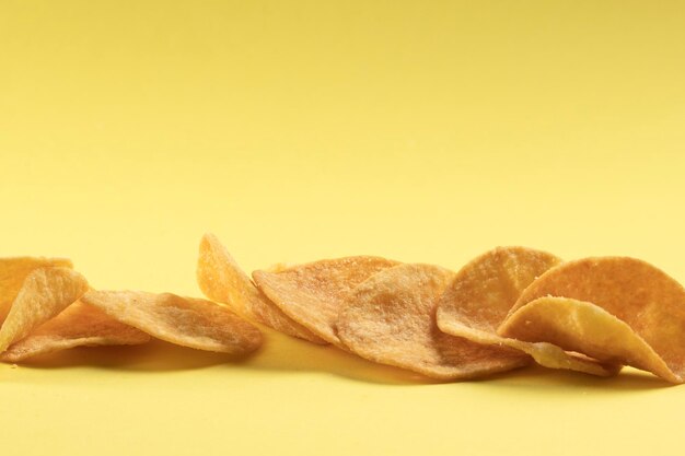 Aardappelchips verspreid over de tafel close-up op een gele achtergrond Voedsel met een verhoogd cholesterolgehalte