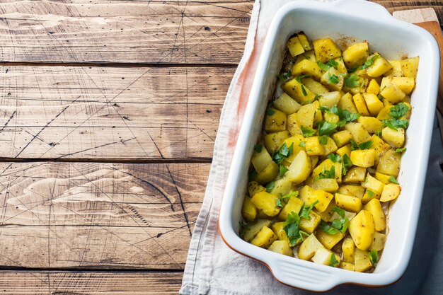 Aardappelen gebakken met specerijen en kruiden in een keramische bakplaat. Vegetarische keuken. Ruimte kopiëren