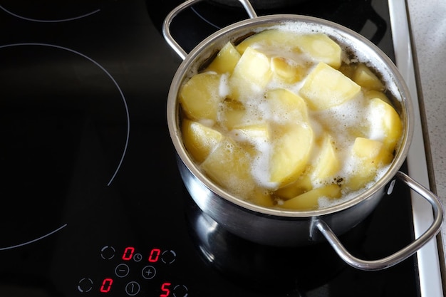 Foto aardappelen koken in een kleine metalen pan op de inductie kachel in de keuken