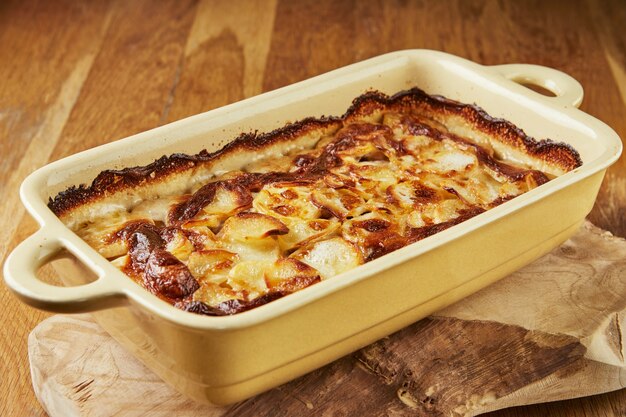 Aardappelen met champignons in speciale vorm op houten standaard na bakken in de oven. Stap voor stap recept.