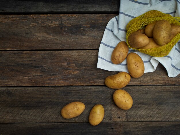 Aardappelen op oude houten tafel.