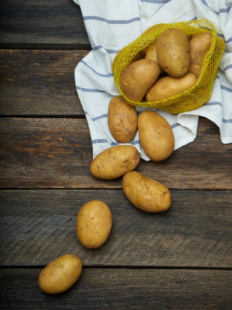 Aardappelen op oude houten tafel.