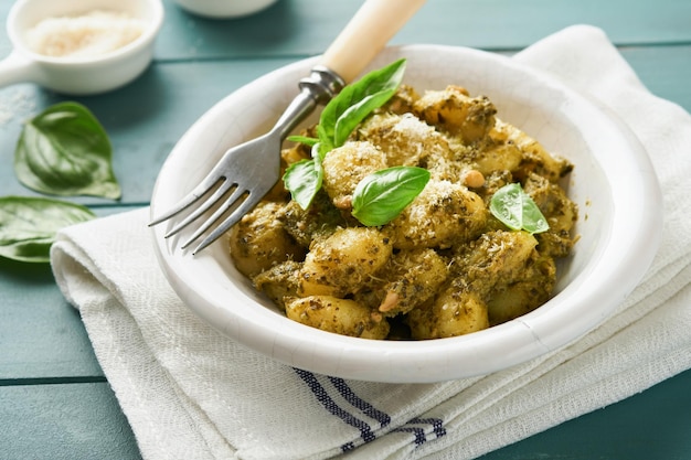 Aardappelgnocchi Traditionele zelfgemaakte aardappelgnocchi met saus pesto keukentafel en basilicum op oude rustieke turquoise keukentafel Traditioneel Italiaans eten Traditioneel Italiaans eten Top uitzicht