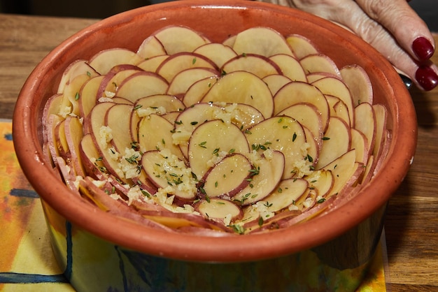 Aardappelgratin in bloemvormige keramische schaal is klaar om in de oven te bakken