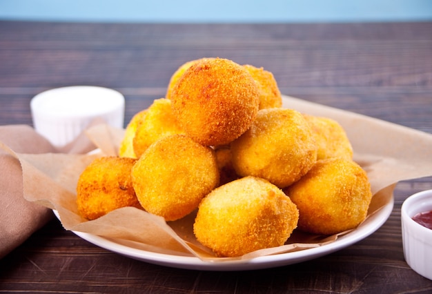 Aardappelkroketten balletjes op het bord en dipsauzen.