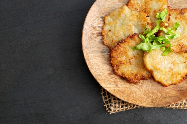 Aardappelpannenkoekjes, draniki, deruny, aardappel latkes, raggmunk of boxties op houten plaat.