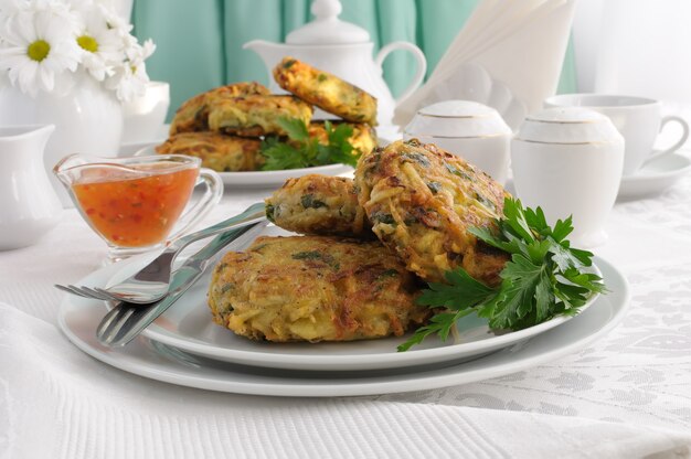 Aardappelpannenkoekjes met groenten, saus op het bord