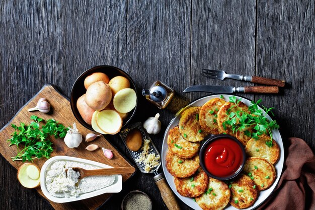 Aardappelpannenkoekjes met kwark met knoflook, peterselie, geserveerd met ketchup op een bord op een houten ondergrond, bovenaanzicht, close-up