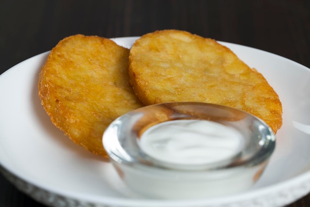 Aardappelpannenkoekjes met zure room op een bord, een traditioneel Wit-Russisch gerecht van verse aardappelpannenkoekjes met zure room