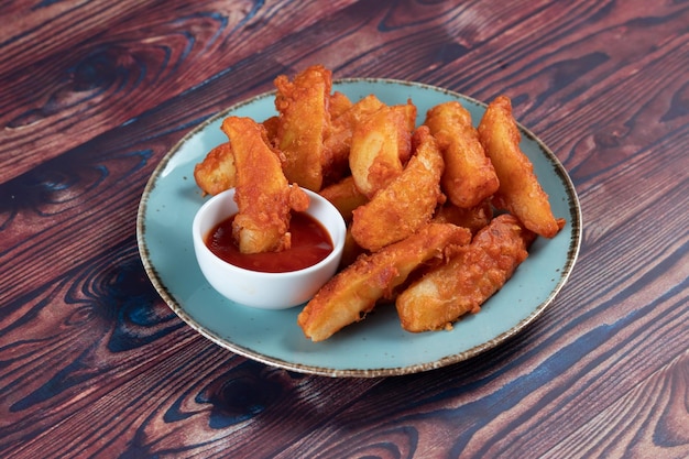 Aardappelpartjes met tomatensaus geserveerd in schotel geïsoleerd op achtergrond zijaanzicht van fastfood