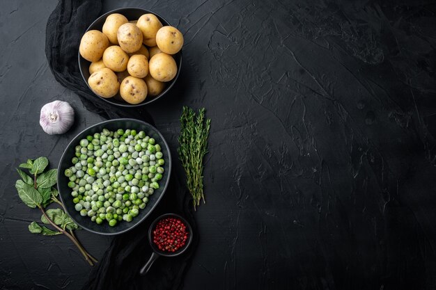 Aardappelpuree ingrediënten met groene erwten en munt, plat leggen, op zwarte tafel