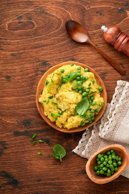 Aardappelpuree met boter, erwten, uien, basilicum in een witte kom