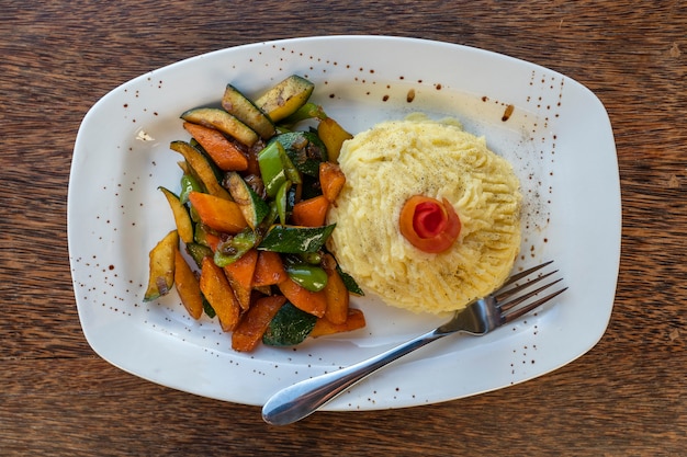 Aardappelpuree met gebakken groenten op een witte plaat