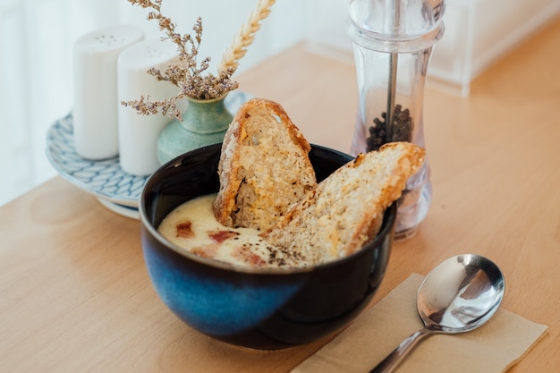 Aardappelsoep met spek en geserveerd met zuurdesembrood op de houten tafel