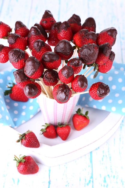 Aardbei in chocolade op spiesjes in beker op tafel close-up