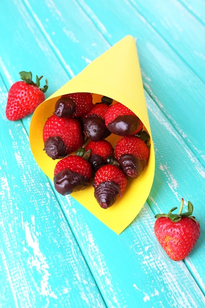 Aardbei in chocolade op spiesjes in papieren zak op tafel close-up