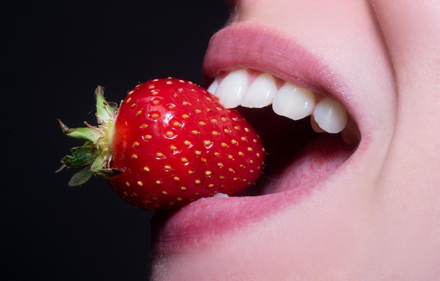 Aardbei in lippen gezonde tanden rode aardbei in de mond van de vrouw close-up