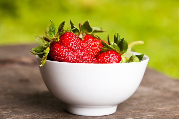 Aardbei met kom op houten tafel buiten