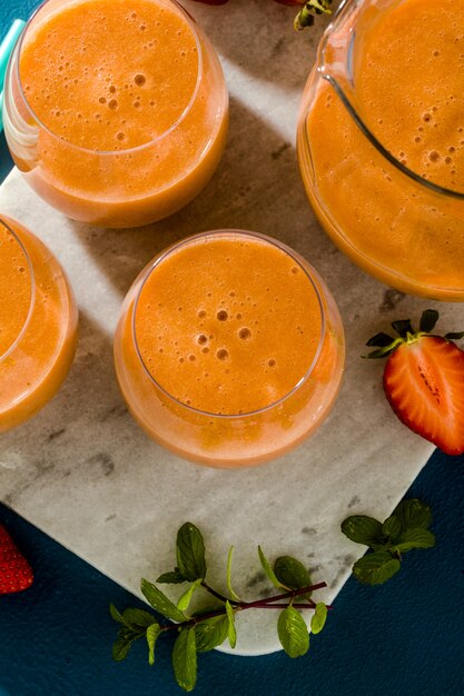 Aardbei smoothies in een karaf en glazen op een blauwe achtergrond. rauw ontbijt