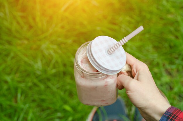 Aardbei smoothies ter beschikking en tennisschoenen op een achtergrond van groen gras