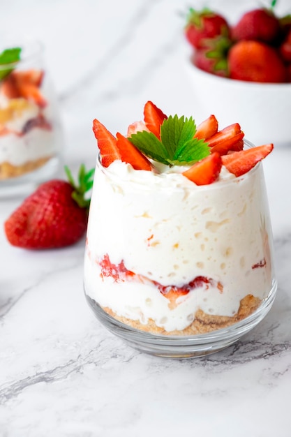 Foto aardbei trifle dessert met vla cake kruim en verse aardbei in glas op marmer