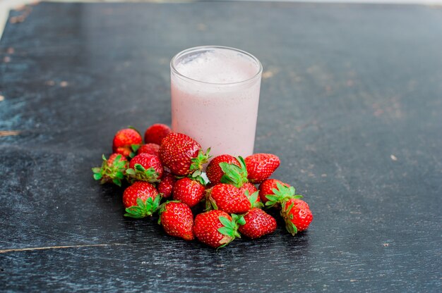 Aardbeien en een glas melk op oude houten achtergrond