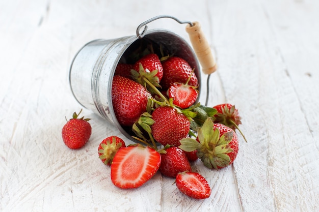 Aardbeien in een emmer op een witte houten tafel