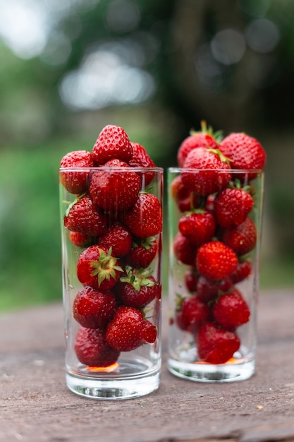 Aardbeien in een glas op een houten tafel in de tuin. Sap concept. Zomertijd