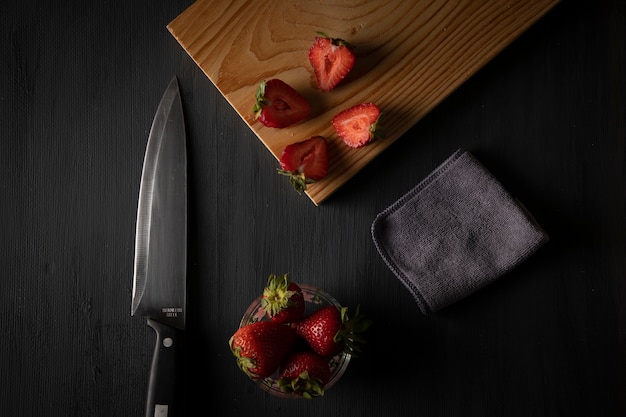 Aardbeien in een kom op een tafel met een snijplank en een mes ernaast