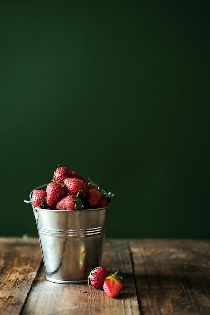 Aardbeien in een metalen emmer Verse aardbeien in een kom op een houten tafel