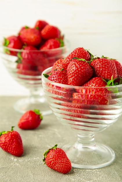 Aardbeien in glazen bekers op lichte achtergrond Verticale foto