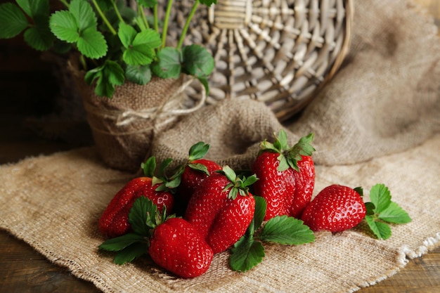 Aardbeien met bladeren op op zak servet op houten achtergrond