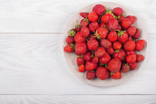 Aardbeien op een bord op een witte houten achtergrond