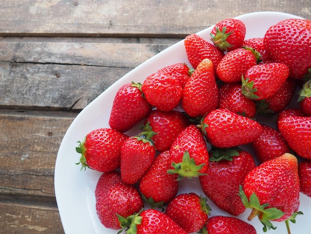 Aardbeien op een plaat houten achtergrond witte gerechten en heerlijke rode grote tuinaardbeien