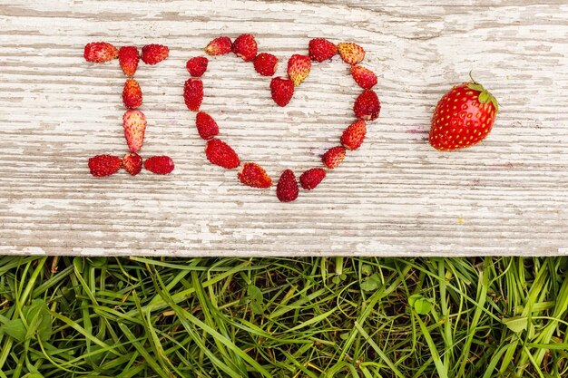 Aardbeien zijn neergelegd in de letters op een achtergrond van groen gras en karton