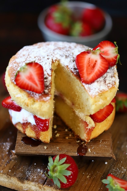 Aardbeienbiscuitgebak met verse aardbeien en room.