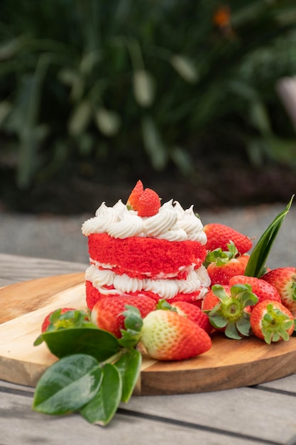 Aardbeiencake met witte chocoladecrème en aardbeien rond op rustieke tafel buiten de tuin wazige achtergrond