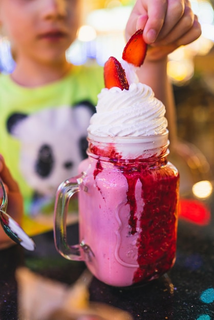 Aardbeienmilkshake in een mooi glas in een café drinkt een kind een milkshake