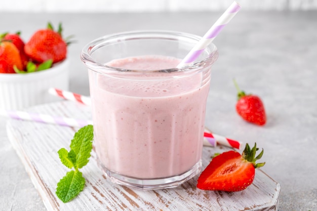 Aardbeienmilkshake of smoothiecocktail in de glazen pot op een grijze betonnen achtergrond Kopieer de ruimte