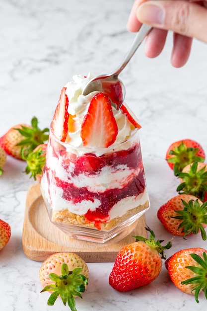 Aardbeienmoussecake in een glas op een marmeren tafel de duidelijk gelaagde aardbeienmoussecake is prachtig versierd met gesneden verse aardbeien